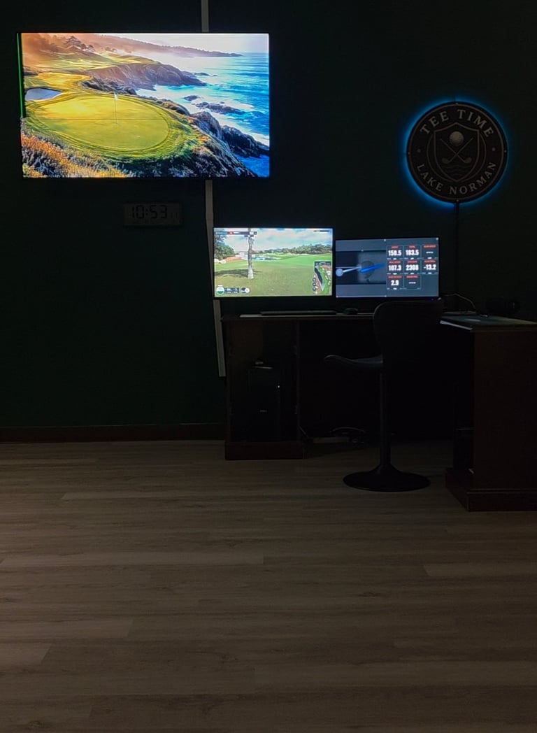 Dark golf simulator room with multiple monitors displaying courses and stats, wooden floor, and glowing blue golf club logo on wall